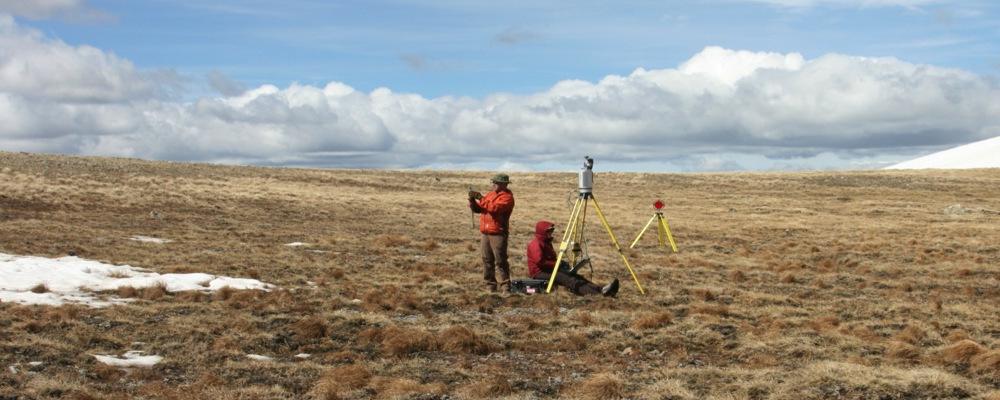 Two people in a field performing lidar survey measurements